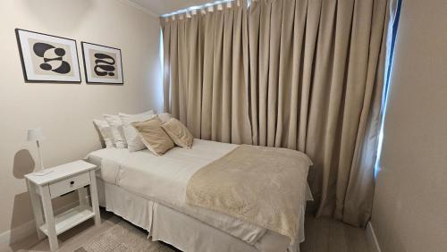 a white bedroom with a bed and a window at LUUM by Norus in Santiago