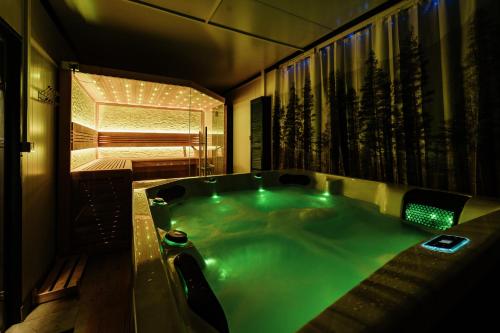 a jacuzzi tub with green lighting in a bathroom at Jurty za winklem ze strefą SPA in Rudnica