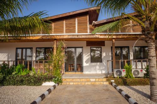 a house with a palm tree in front of it at The Bali Resort Zanzibar in Pingwe