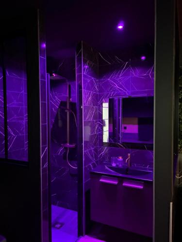 a purple bathroom with a sink and a mirror at La Romantique in Bressuire