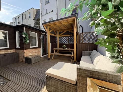 a patio with a couch and a table on a building at Coastal Comfort Seaside Cabin with Spacious Garden in Margate
