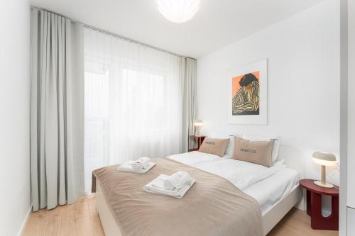 a white bedroom with a bed with towels on it at Apart111 Apartamenty Bałtycka 22 in Kołobrzeg