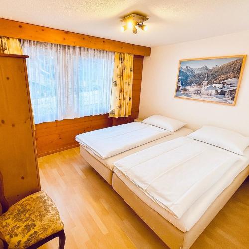 ein Schlafzimmer mit zwei Betten und einem Fenster in der Unterkunft Chaletwohnung Thilo in Lenk im Simmental