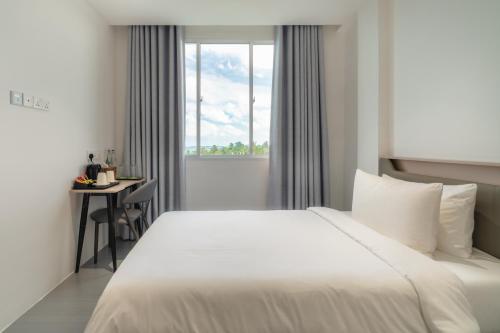 a bedroom with a bed and a desk and a window at Nest by Hawks Hotels Kamadhoo Baa Atoll in Kamadhoo