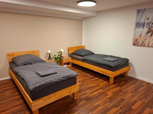 two beds in a room with wooden floors at Gemütliches Apartment in Giengen an der Brenz