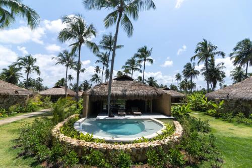 a resort with a swimming pool and palm trees at Primitivo Hotel & Villas in Passo de Camarajibe