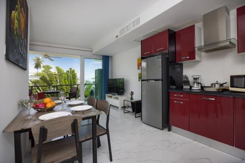 a kitchen with red cabinets and a table with chairs at Woodbridge Property at Karon Butterfly in Karon Beach
