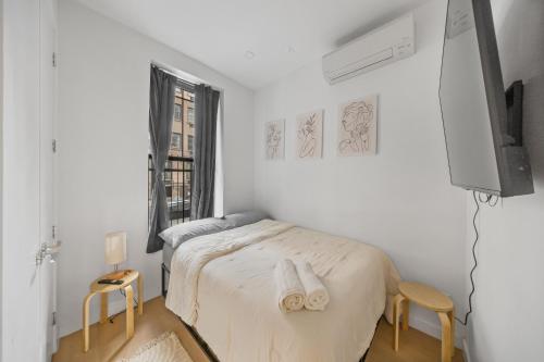 a white bedroom with a bed and a tv at Double Room at a shared Apartment near Times Square in New York