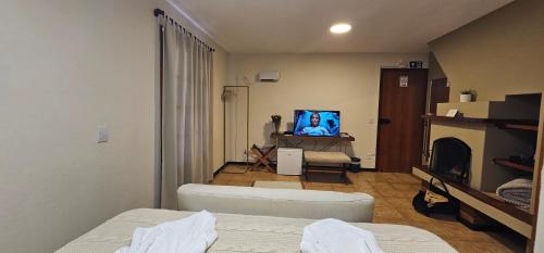 a living room with a couch and a tv at Pousada Flor de Lua Monte Verde in Monte Verde