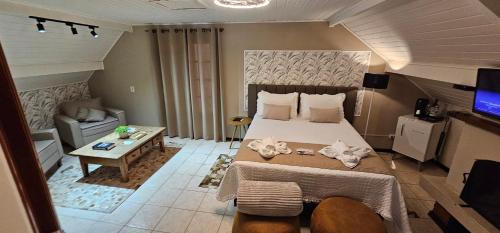 a bedroom with a large bed and a living room at Pousada Flor de Lua Monte Verde in Monte Verde