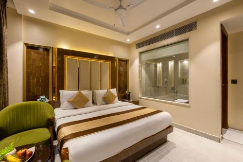 a bedroom with a large bed and a green chair at Hotel Grand Plaza in City Centre - Walking Distance From New Delhi Railway Station and Connaught Place in New Delhi