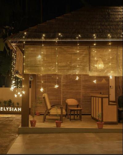 a patio with a chair and a table and lights at The Elysian Boutique Stays - Havelock in Havelock Island