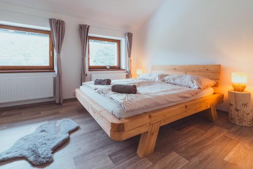 a bedroom with a large wooden bed with two windows at DOMEK Písařov - apartmány in Písařov
