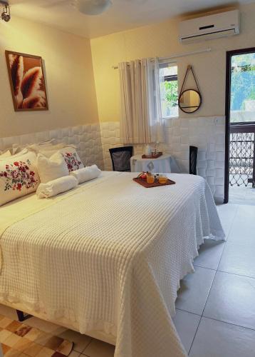 a bedroom with a white bed with a tray on it at Pousada Recanto da Família in Natal