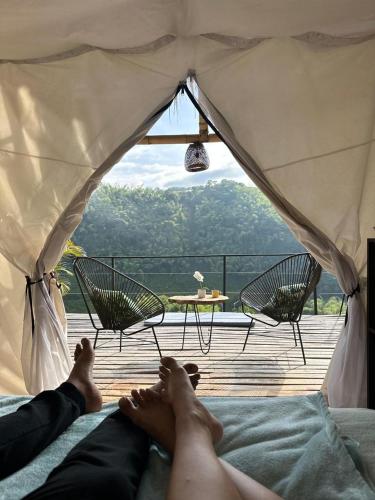 una persona acostada en una cama con los pies dentro de una tienda de campaña en Encanto Toscano, en Quimbaya