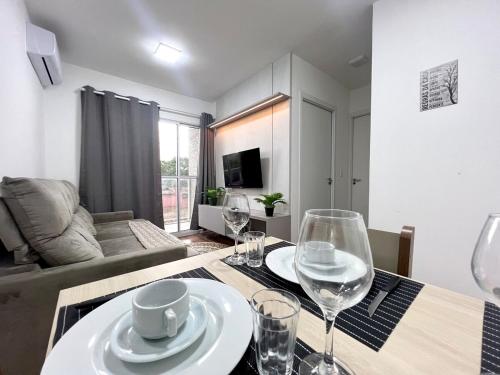 a dining room table with wine glasses and a living room at Apartamento Inteiro - 2 Quartos com AC - Wifi 1000mb - Piscina - 1 Vaga de Garagem - Elevador - Sacada Gourmet - Indicado para Grupos, Hospedes a Trabalho, Família e Pets in Toledo
