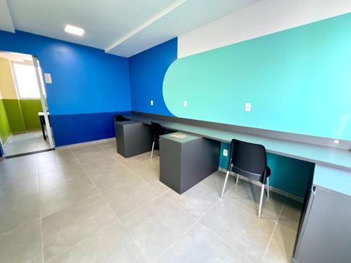 an empty room with blue walls and desks and chairs at Apartamento Inteiro - 2 Quartos com AC - Wifi 1000mb - Piscina - 1 Vaga de Garagem - Elevador - Sacada Gourmet - Indicado para Grupos, Hospedes a Trabalho, Família e Pets in Toledo