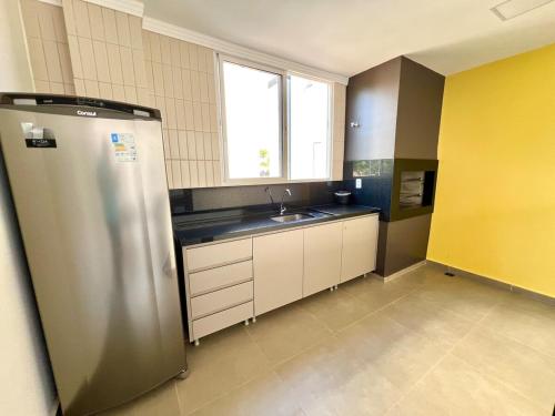 a kitchen with a stainless steel refrigerator and a sink at Apartamento Inteiro - 2 Quartos com AC - Wifi 1000mb - Piscina - 1 Vaga de Garagem - Elevador - Sacada Gourmet - Indicado para Grupos, Hospedes a Trabalho, Família e Pets in Toledo