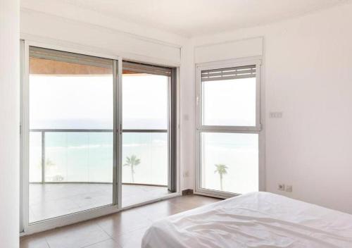 a white bedroom with large windows and a bed at O&O Group - Stunning Sea View 3 BR Apartment Iconic Tower in Bat Yam