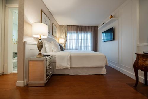 a bedroom with a bed and a lamp on a dresser at Villa do Vale Boutique Hotel in Blumenau