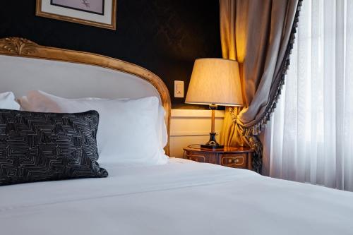 a bedroom with a bed with a black pillow and a lamp at Villa do Vale Boutique Hotel in Blumenau