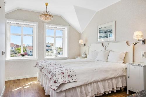 1 dormitorio con 1 cama con colcha blanca y 2 ventanas en Lotshotellet en Käringön
