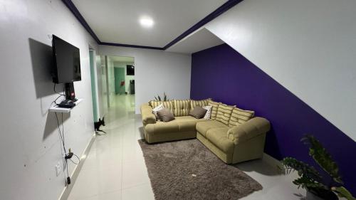 een woonkamer met een bank en een paarse muur bij Laiara in Ilhéus