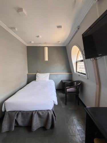 a bedroom with a bed and a flat screen tv at Hotel Fundador in Santiago