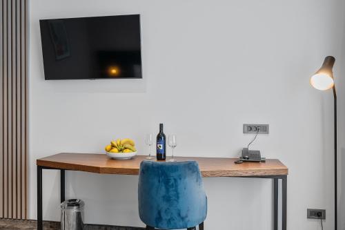 a table with a blue chair and a television on a wall at iNova in Zagreb