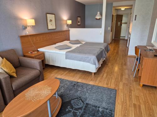 a hotel room with a bed and a couch at Ikaalisten Kylpylä Apartamentos rantahuoneisto Terme in Ikaalinen