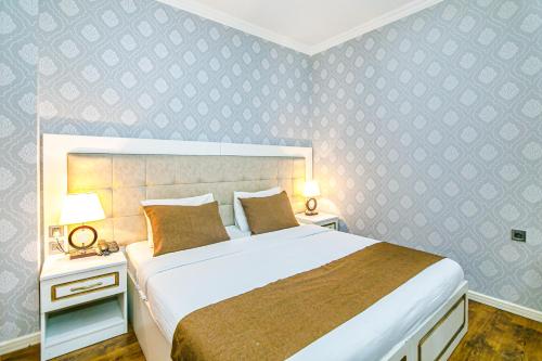 a bedroom with a large bed and two night stands with lamps at Maris Hotel Baku in Baku