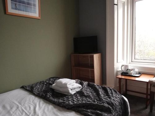 a bedroom with a bed and a desk and a window at Greenland house in Castletown