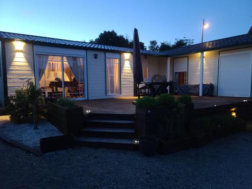 una casa con un ponte e un patio di notte di Chalet Du Bonheur Lac De Guerledan a Caurel