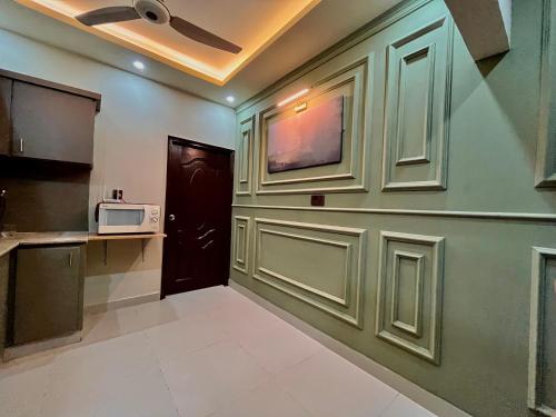 a corridor of a kitchen with a door and a microwave at 1-BHK Velvet Keys Executive Suite Near Clifton Beach in Karachi