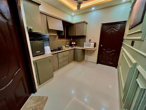 a small kitchen with brown cabinets and a white tile floor at 1-BHK Velvet Keys Executive Suite Near Clifton Beach in Karachi