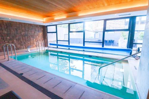 a large swimming pool with blue water in a building at HOM I 2D2B Parking, piscina temperada y gimnasio in Puerto Varas