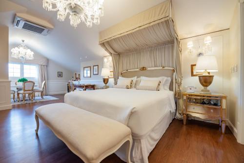 a bedroom with a large white bed and a chandelier at Villa do Vale Boutique Hotel in Blumenau
