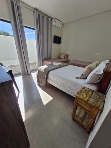 a bedroom with a bed and a chair and a window at Pousada Lobo Guará in São João Batista do Glória
