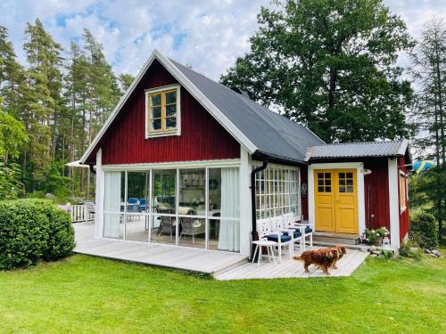 a red house with a dog standing in front of it at 7 person holiday home in HALLABRO in Hallabro