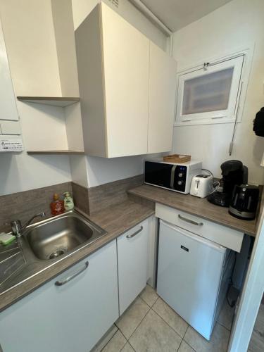 a small kitchen with a sink and a microwave at Studio lumineux de 23m avec balcon in Bagnoles de l'Orne
