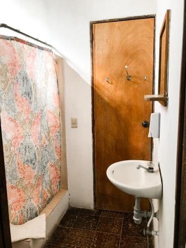 a bathroom with a sink and a wooden door at Hostal Casa del Sol in Suchitoto
