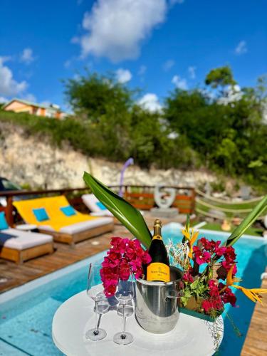 a table with a bucket of flowers and a bottle of champagne at Villa Iséa - Piscine privée & Terrasse Vue Mer in Le Gosier