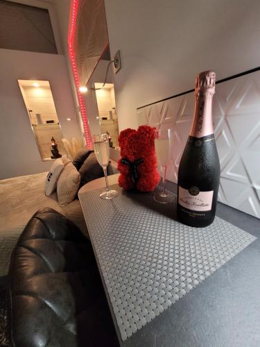 Secret Love Jacuzzi ou Midnight Spa في بلوا: زجاجة من الشمبانيا وكأسين على سرير