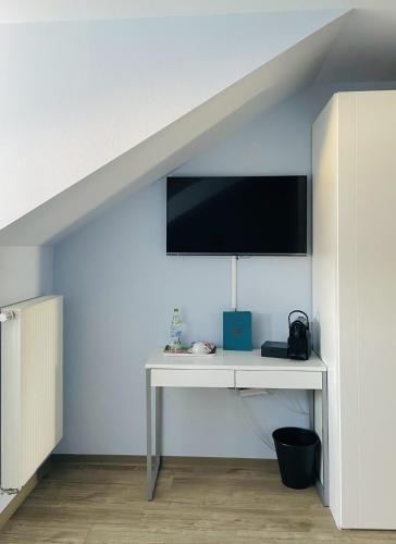 a white desk with a tv on a wall at Das SinGold Hotel mit Highspeed WLAN und digitalem Schlüssel in Schwabmünchen