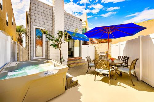a hot tub on a patio with a table and umbrella at Perfect Newport Beach Location With Spa I in Newport Beach