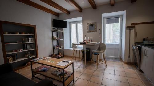 Una sala de estar con una mesa y una cocina. en Le Petit Mona Althéa, en Civaux