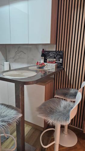 a kitchen with a counter with two chairs and a table at Anamasi in Novi Sad
