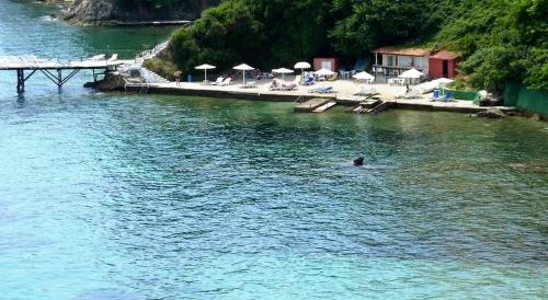 a person swimming in the water next to a beach at Hotel Perama in Perama