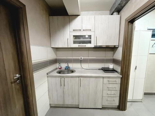 a small kitchen with a sink and a microwave at Apartmani Kristina & Kriss in Užice