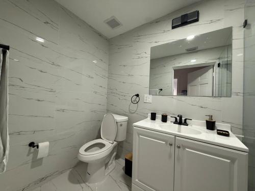Un baño blanco con inodoro y lavabo. en Dania Beach 4-bedroom house - Pool,Parking,Grill, en Dania Beach